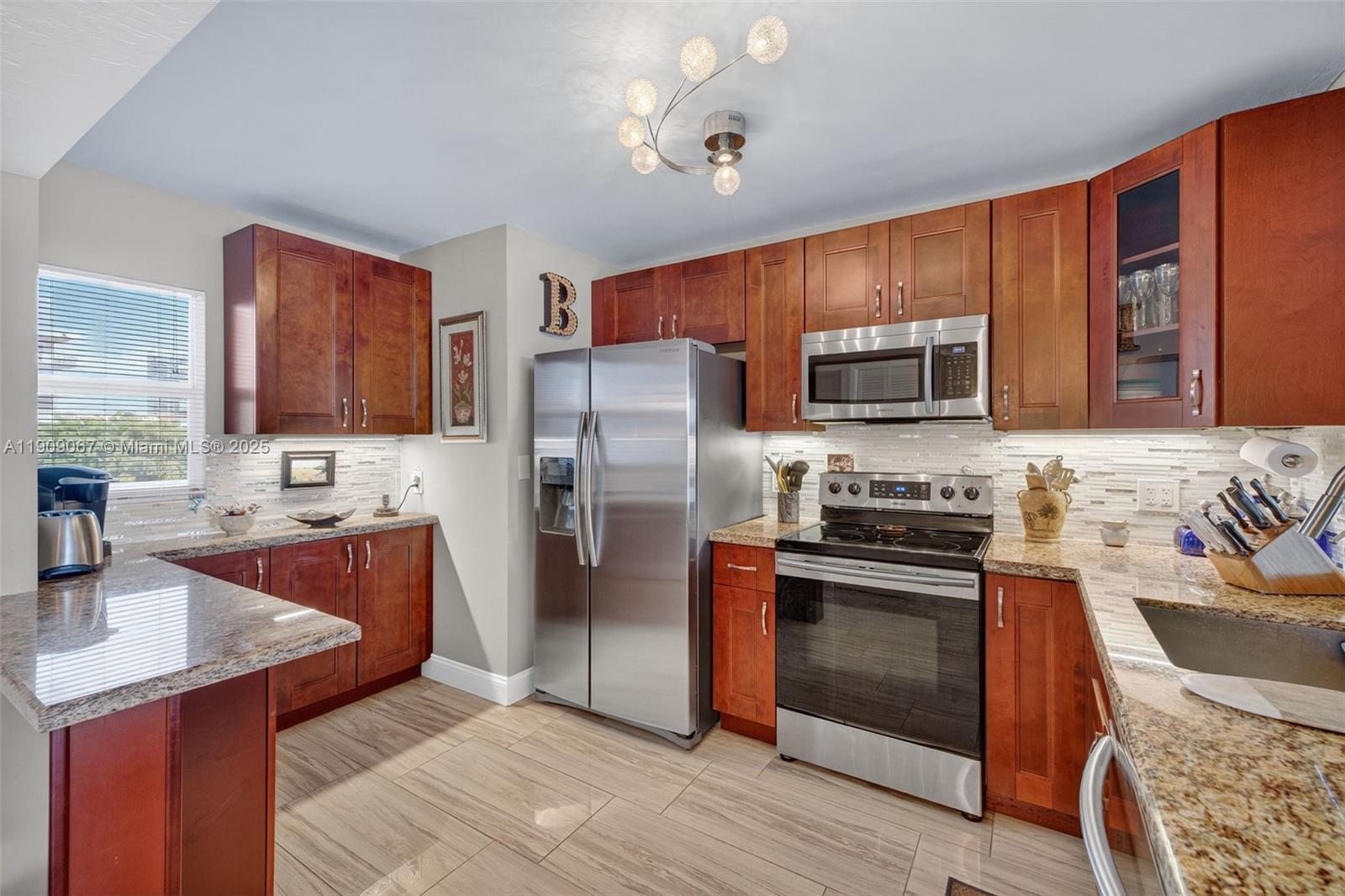 121 Golden Isles Drive, Unit 205 Hallandale Beach, FL 33009 - Photo 13 of 82 a kitchen with stainless steel appliances granite countertop a refrigerator stove microwave and sink