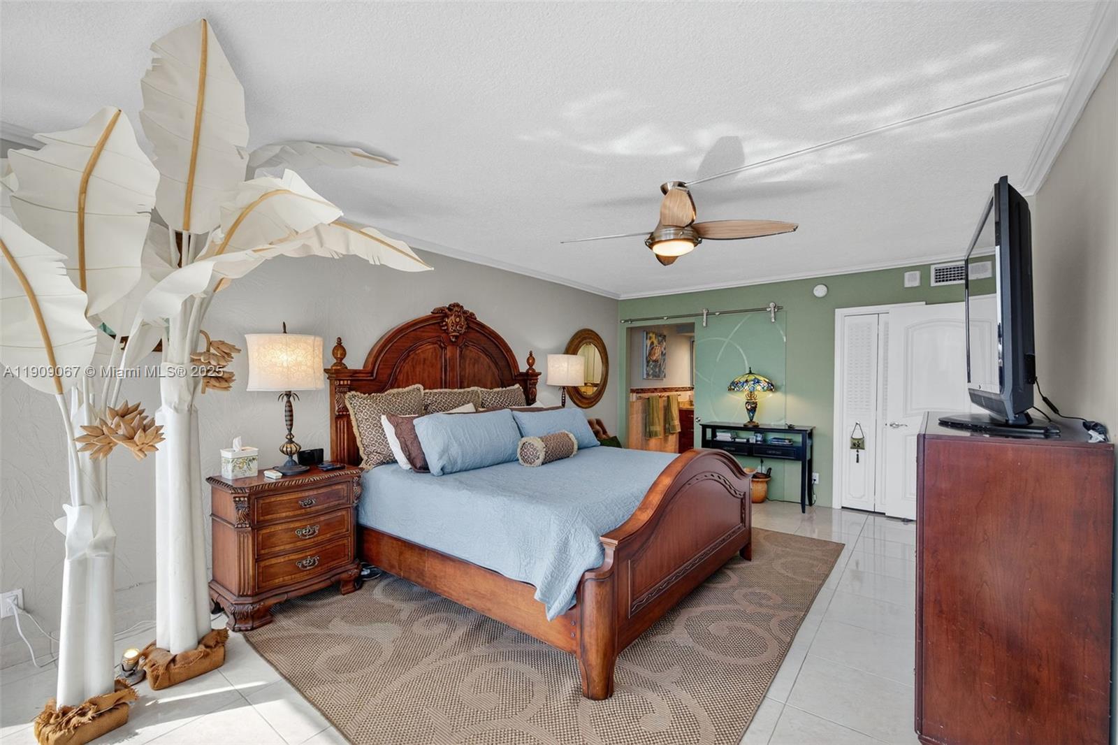 121 Golden Isles Drive, Unit 205 Hallandale Beach, FL 33009 - Photo 29 of 82 a bedroom with a bed a couch and a flat tv screen on the dresser