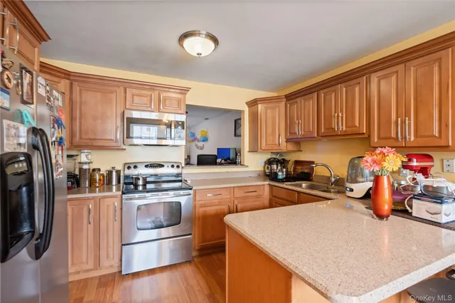 a kitchen with stainless steel appliances granite countertop a stove top oven a refrigerator a sink and dishwasher with wooden floor