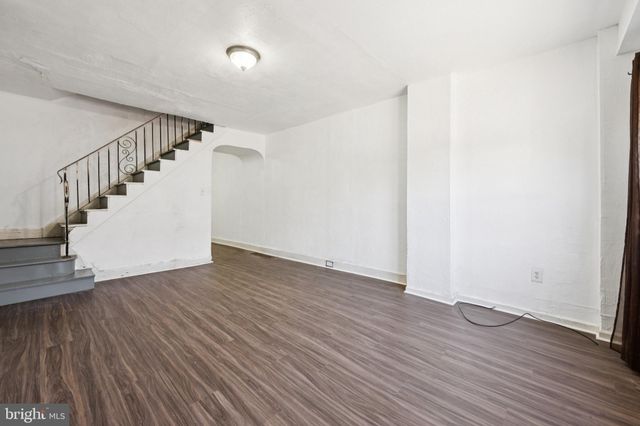 a view of an empty room with wooden floor and stairs