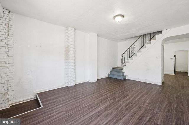 a view of an empty room with wooden floor and stairs