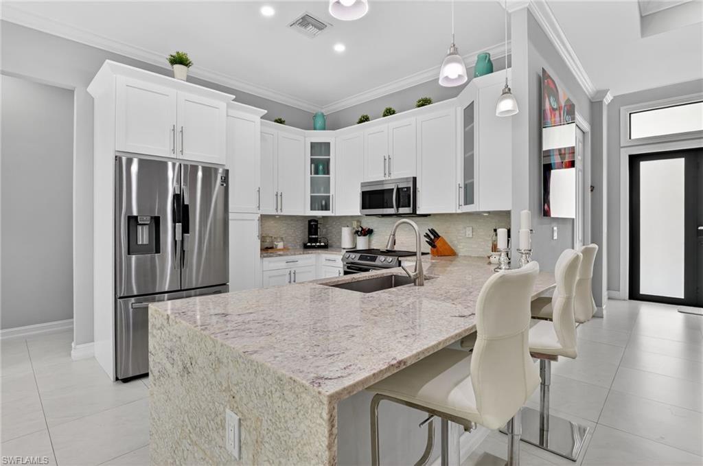 2642 10th Avenue Northeast Naples, FL 34120 - Photo 11 of 38 a kitchen with stainless steel appliances granite countertop a stove refrigerator and microwave