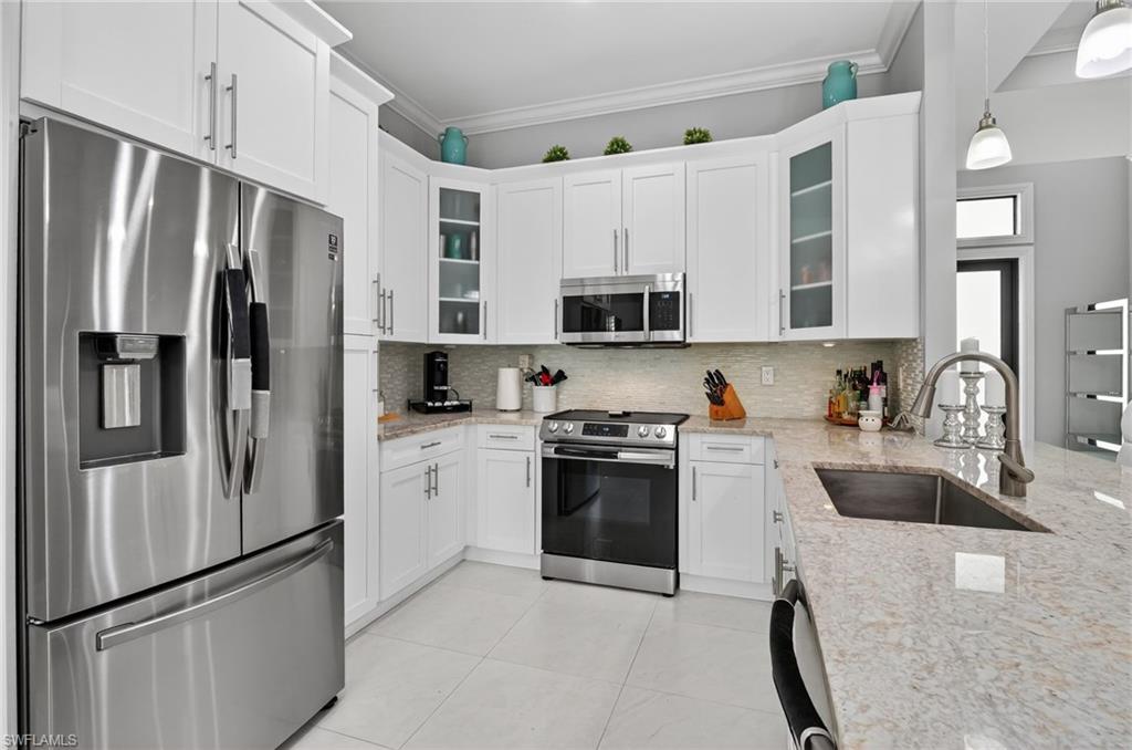 2642 10th Avenue Northeast Naples, FL 34120 - Photo 12 of 38 a kitchen with stainless steel appliances granite countertop a refrigerator stove and sink