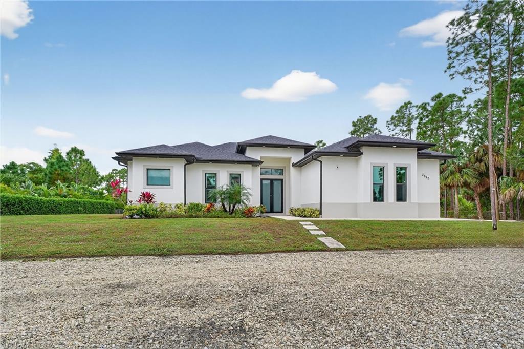 2642 10th Avenue Northeast Naples, FL 34120 - Photo 2 of 38 a front view of a house with a yard and garage