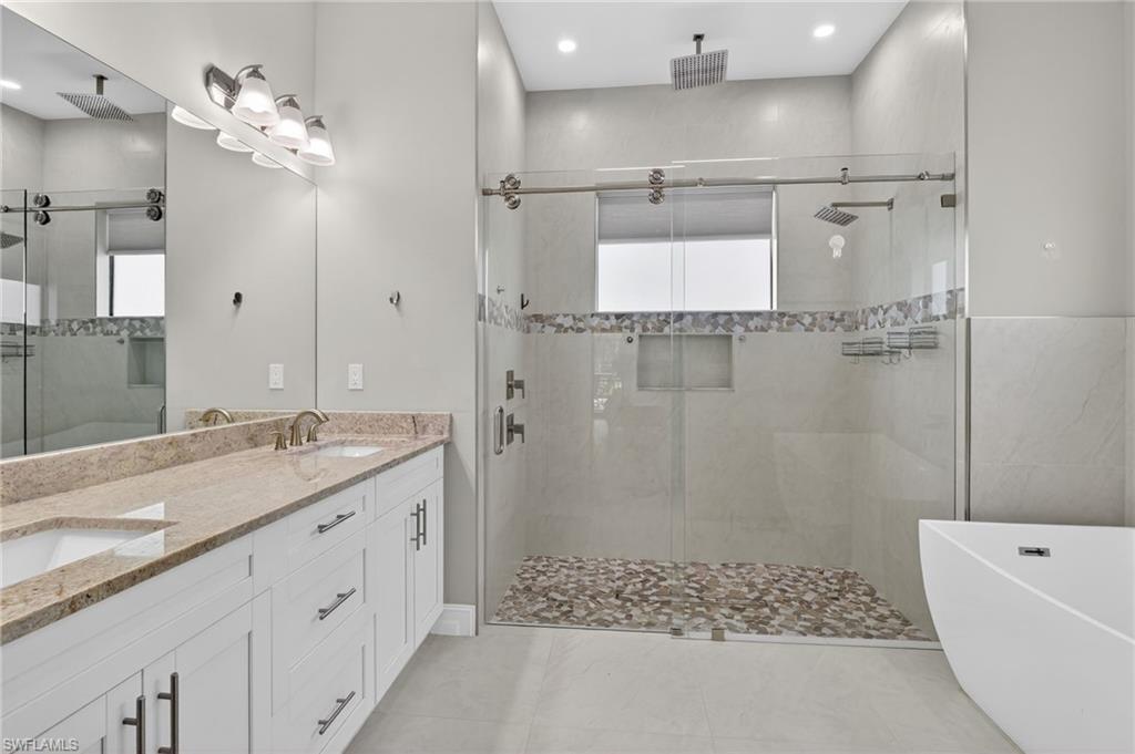 2642 10th Avenue Northeast Naples, FL 34120 - Photo 21 of 38 a bathroom with a granite countertop sink a shower a mirror and a bathtub