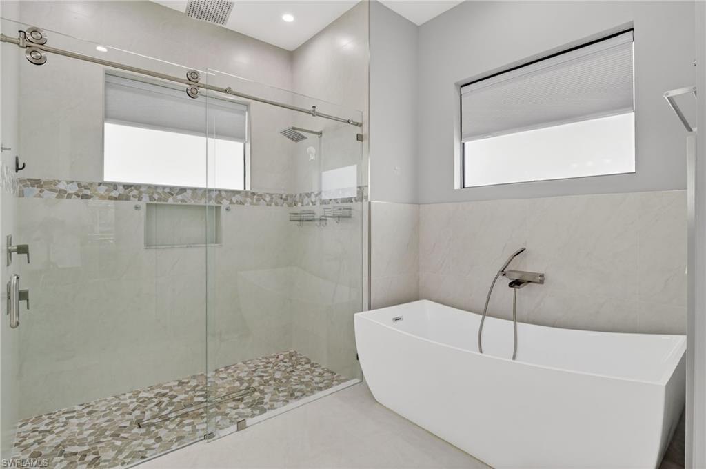 2642 10th Avenue Northeast Naples, FL 34120 - Photo 23 of 38 a bathroom with a white bath tub and a shower