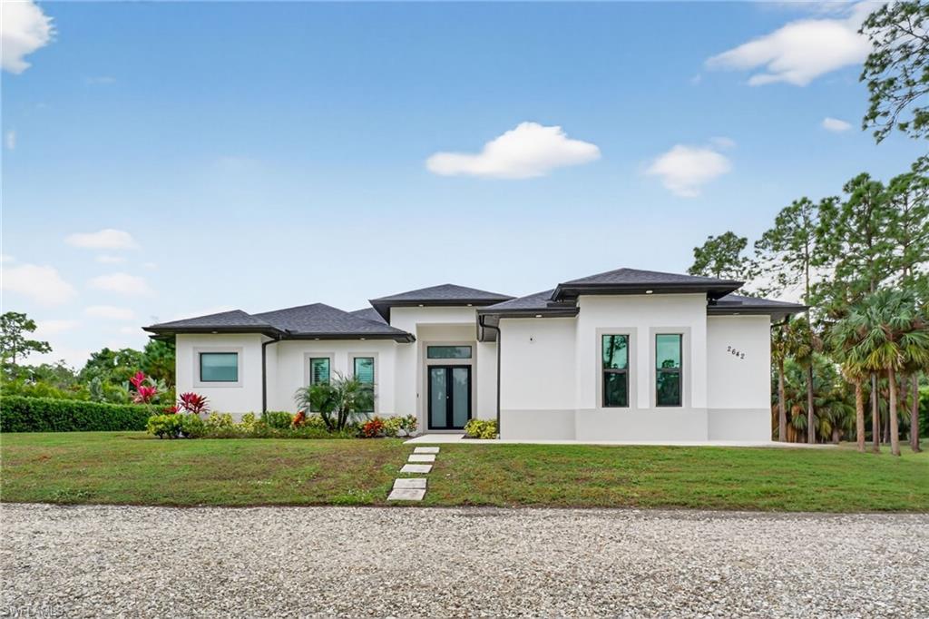 2642 10th Avenue Northeast Naples, FL 34120 - Photo 3 of 38 a view of a white house with a big yard and potted plants