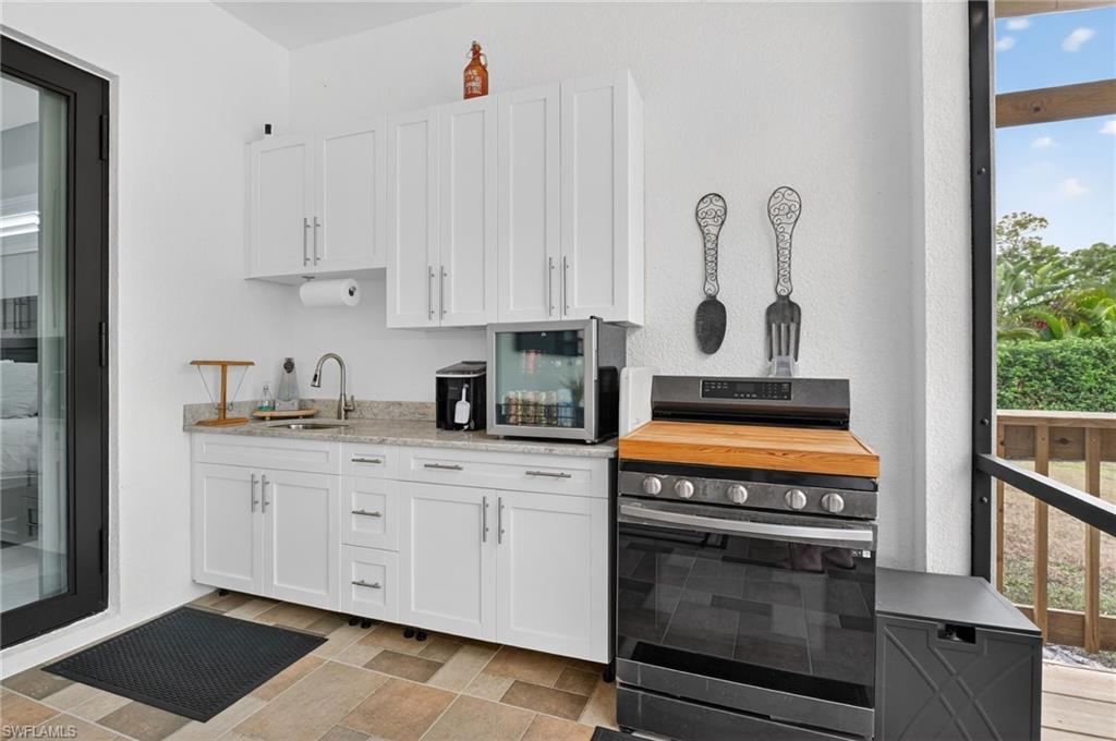 2642 10th Avenue Northeast Naples, FL 34120 - Photo 31 of 38 a kitchen with stainless steel appliances granite countertop a stove a sink and a white cabinets