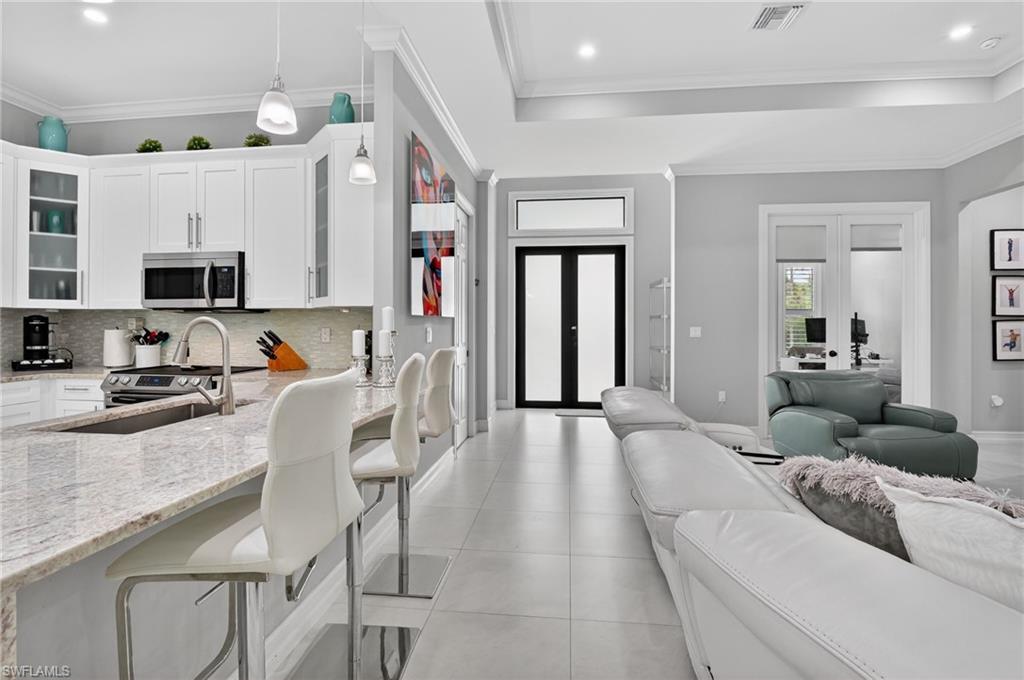 2642 10th Avenue Northeast Naples, FL 34120 - Photo 38 of 38 a living room with stainless steel appliances furniture a fireplace and a flat screen tv