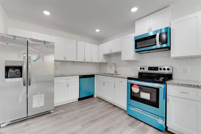 a kitchen with stainless steel appliances granite countertop a stove a sink and a microwave