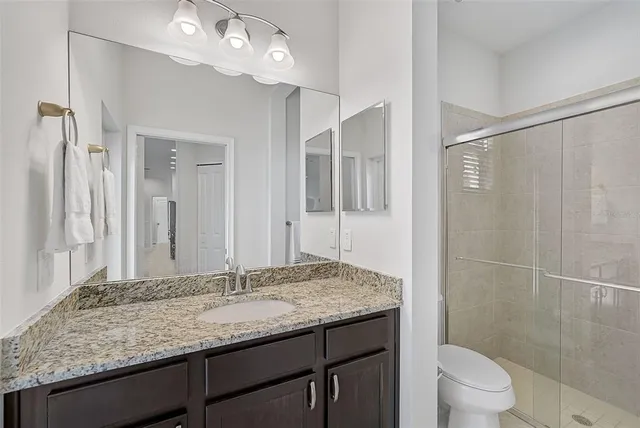 a bathroom with a granite countertop sink toilet and shower