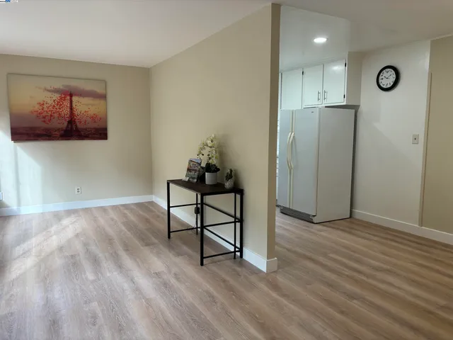 a view of a hallway to room with wooden floor and windows