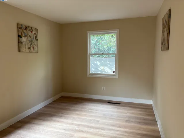 an empty room with wooden floor and window