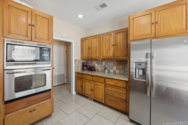 a kitchen with granite countertop stainless steel appliances cabinets and a window