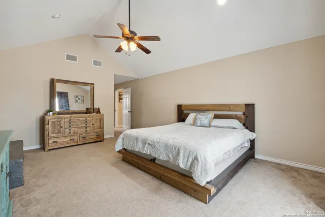 a spacious bedroom with a bed a couch and a chandelier