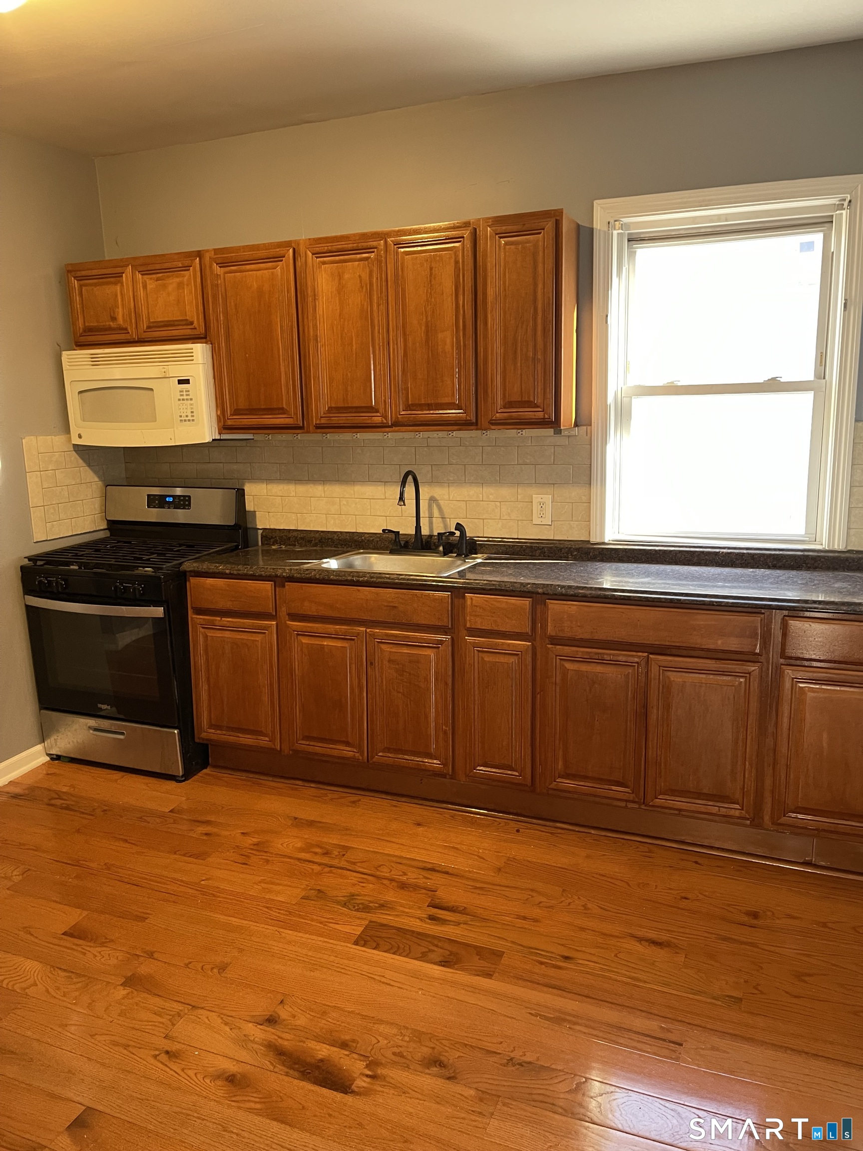 1199 Iranistan Avenue Bridgeport, CT 06605 - Photo 6 of 6 a kitchen with stainless steel appliances granite countertop a sink cabinets and wooden floor