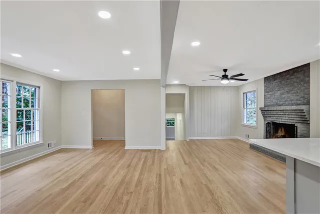 a view of an empty room with wooden floor fireplace and a window