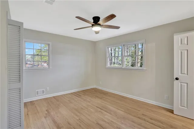 a view of empty room with wooden floor and fan
