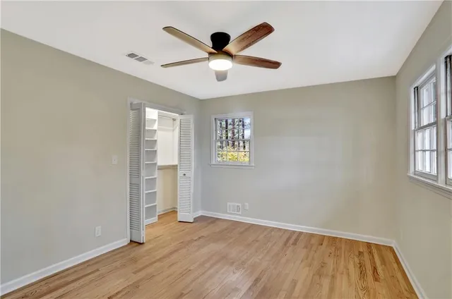 an empty room with wooden floor and windows