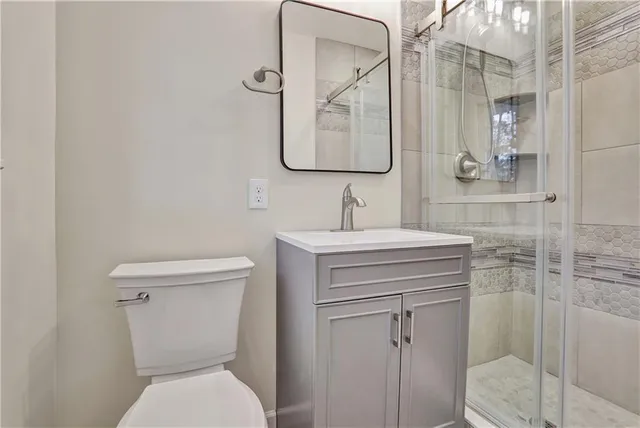 a bathroom with a toilet sink vanity and mirror