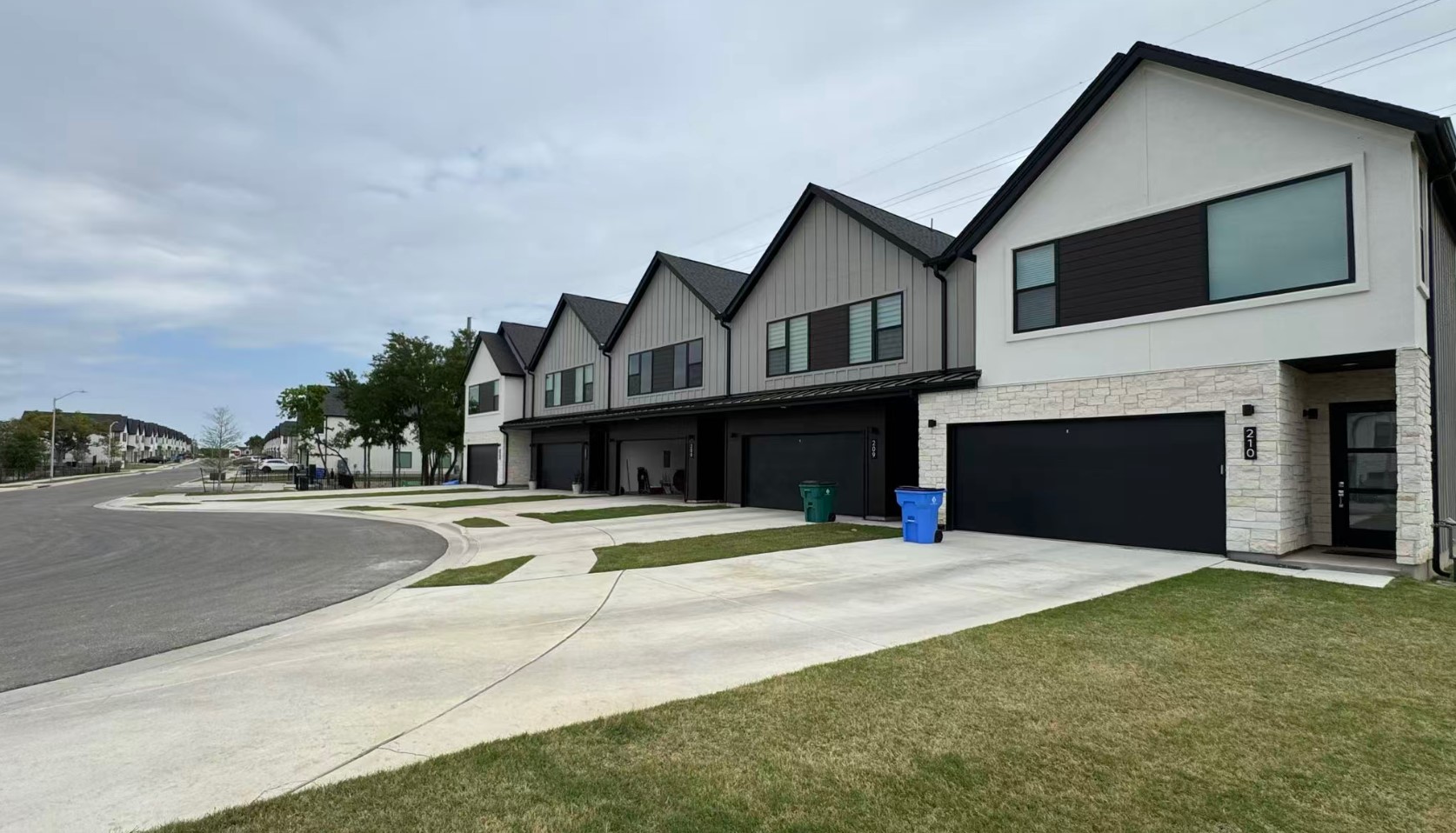 590 Old Mill Road, Unit 210 Cedar Park, TX 78613 - Photo 2 of 4 View of front facade featuring a garage, stone siding, a residential view, concrete driveway, and board and batten siding