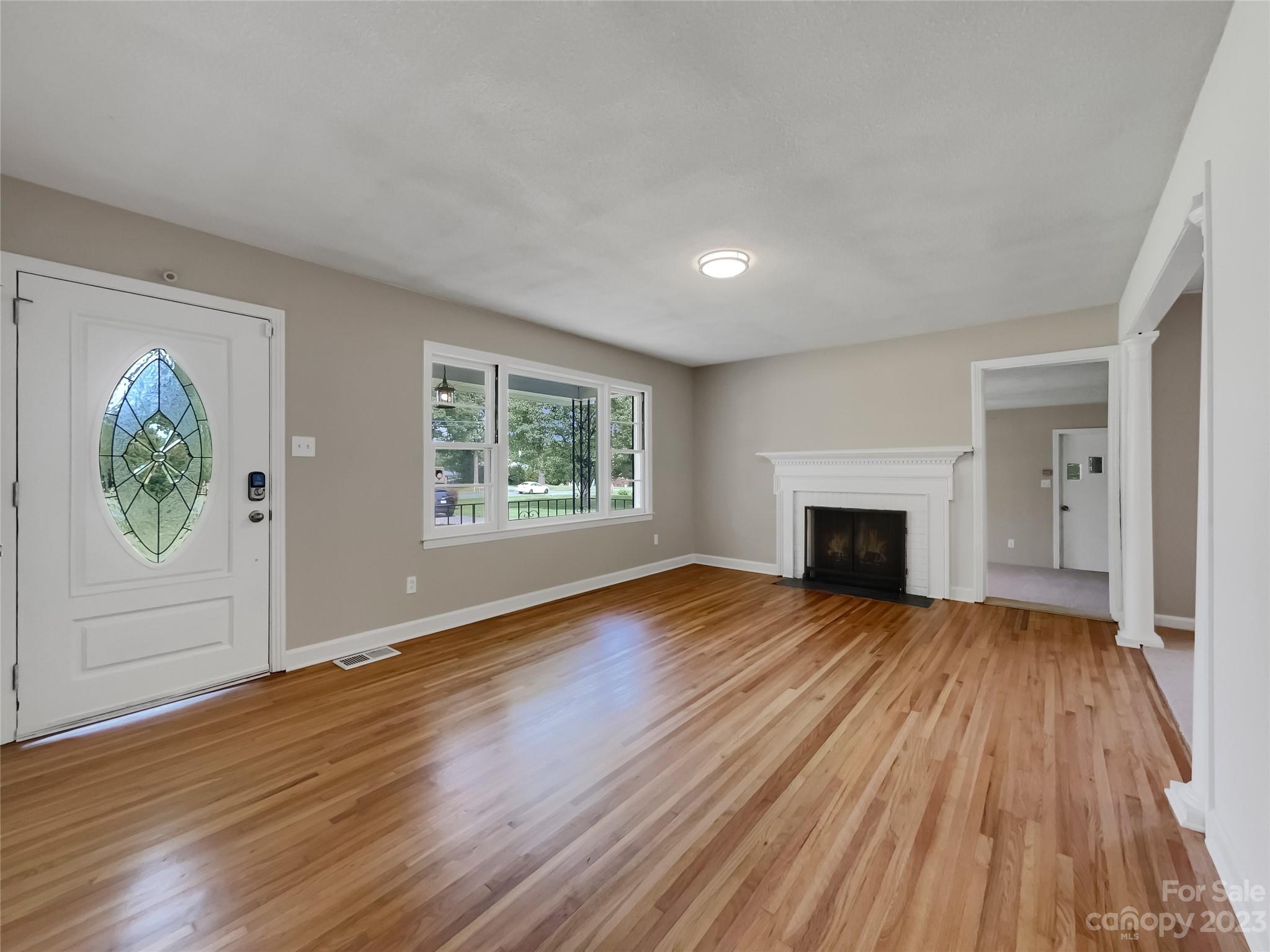 4719 Pleasant Grove Road Waxhaw, NC 28173 - Photo 3 of 24 an empty room with wooden floor fireplace and windows
