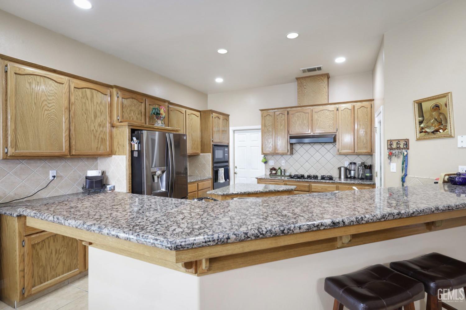 Undisclosed Address Bakersfield, CA 93313 - Photo 19 of 29 a kitchen with kitchen island granite countertop a sink a counter top space cabinets and stainless steel appliances