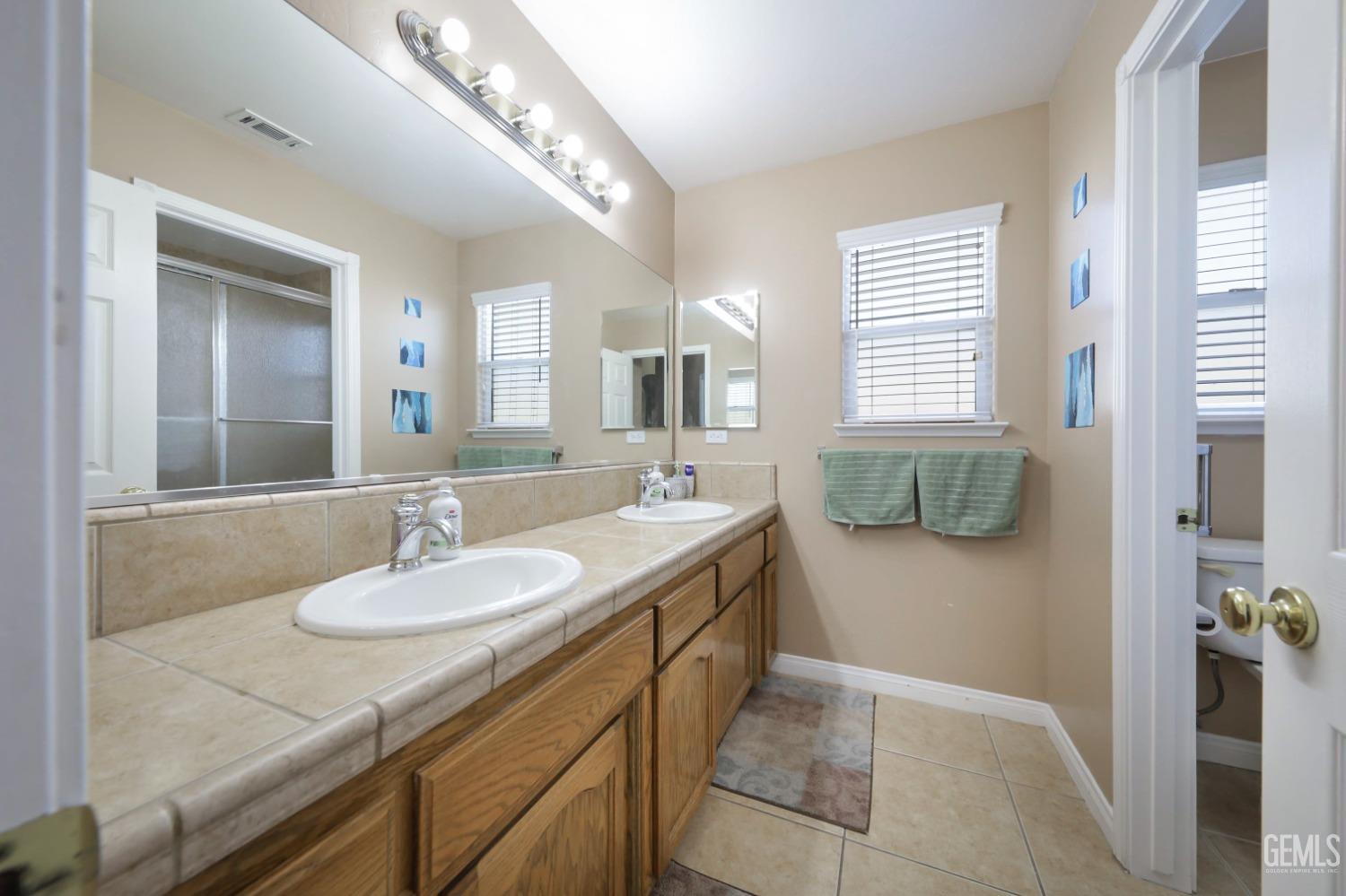 Undisclosed Address Bakersfield, CA 93313 - Photo 7 of 29 a bathroom with a double vanity sink and a mirror