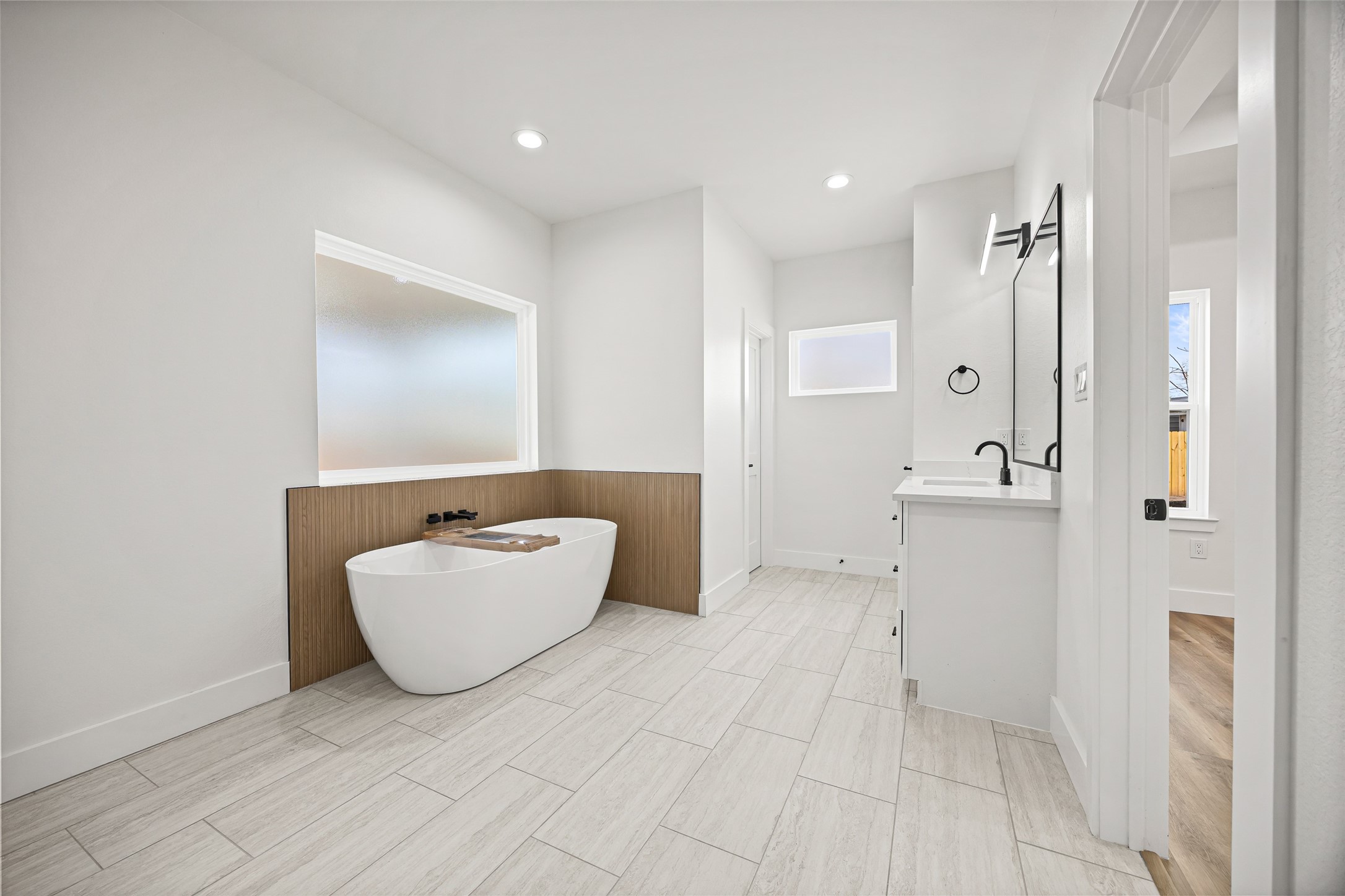 1807 Waco Street Dayton, TX 77535 - Photo 16 of 26 Freestanding soaking tub with fluted tile accent wall in a warm wood-look finish and private frosted window for natural light and privacy.
