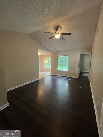 a view of an empty room with a window and wooden floor