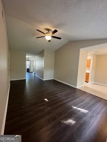 a view of an empty room with wooden floor and a ceiling fan