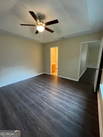 a view of an empty room with wooden floor and a ceiling fan