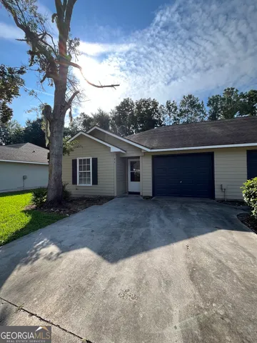 a front view of house with yard and trees in the background
