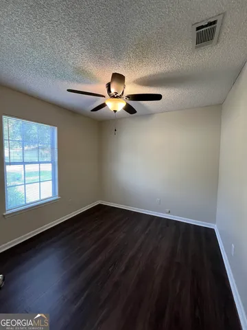 an empty room with wooden floor a ceiling fan and window