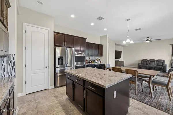 a dining room with stainless steel appliances granite countertop a table chairs and a refrigerator
