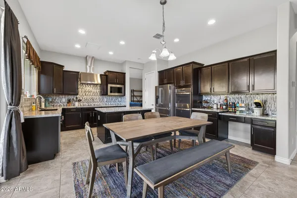 a kitchen with stainless steel appliances granite countertop a stove a refrigerator a kitchen island a dining table and chairs