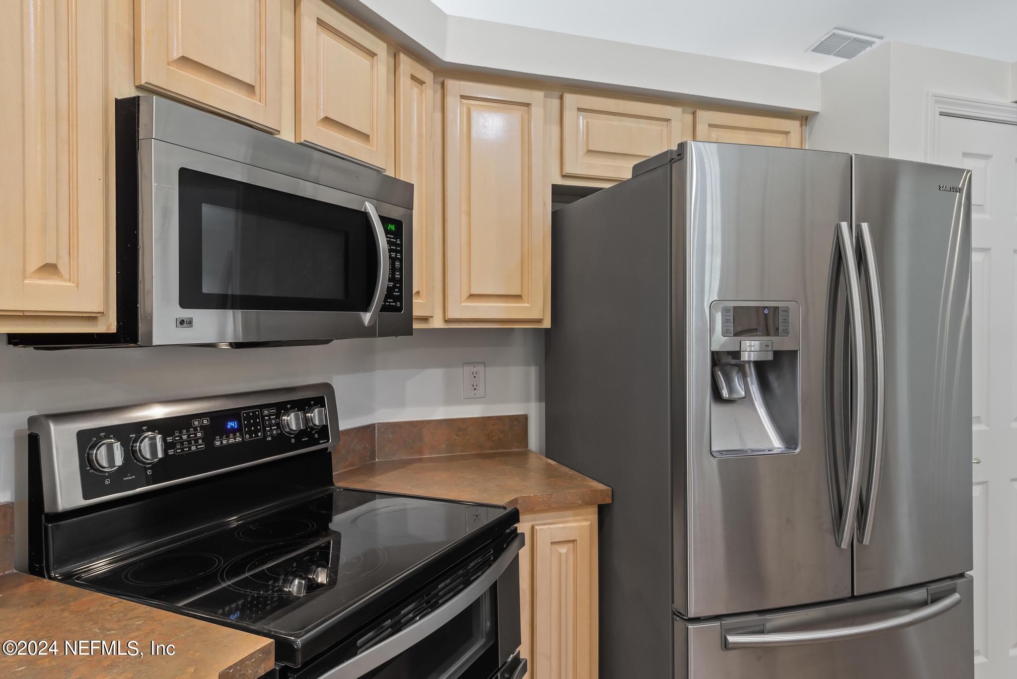 2949 Turning Leaf Lane Jacksonville, FL 32221 - Photo 45 of 116 a kitchen with granite countertop a refrigerator and a stove top oven