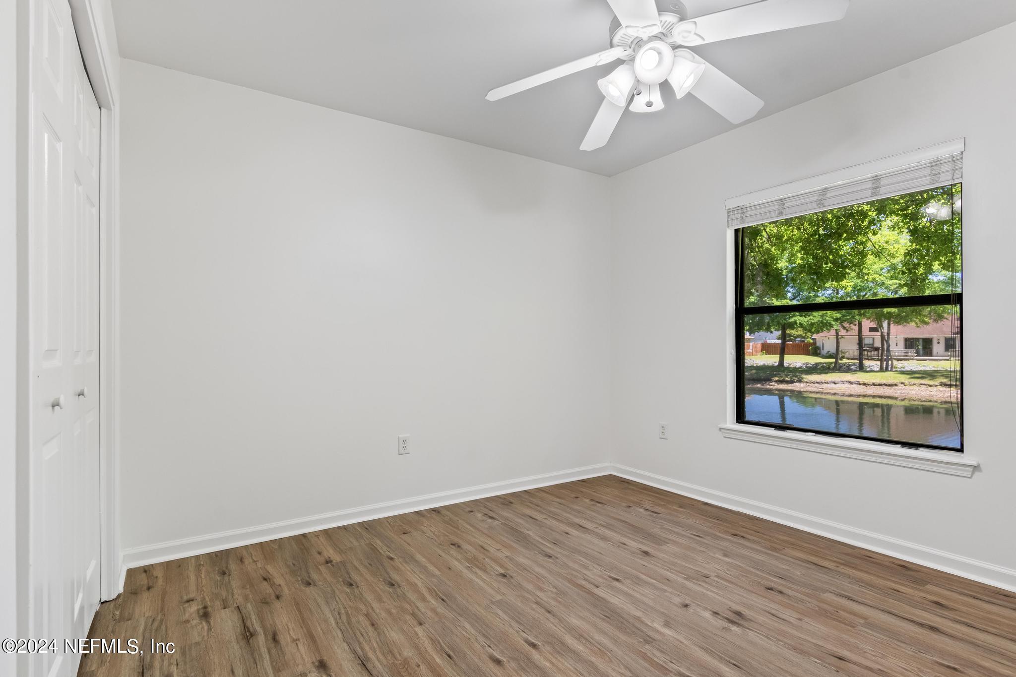 2949 Turning Leaf Lane Jacksonville, FL 32221 - Photo 88 of 116 an empty room with wooden floor chandelier fan and windows