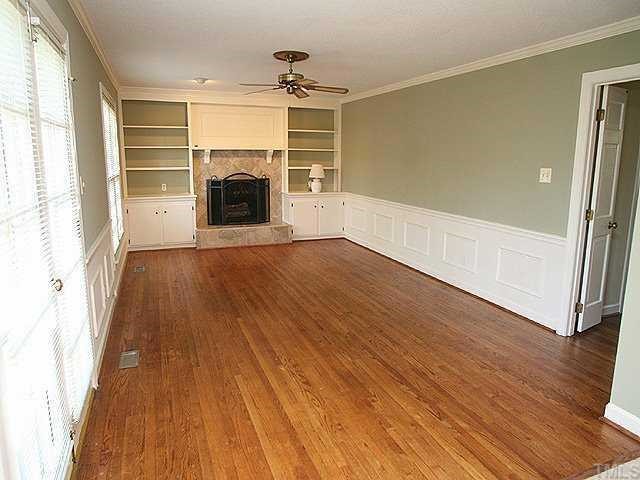 11808 Coachmans Way Raleigh, NC 27614 - Photo 2 of 12 an empty room with wooden floor fireplace and windows