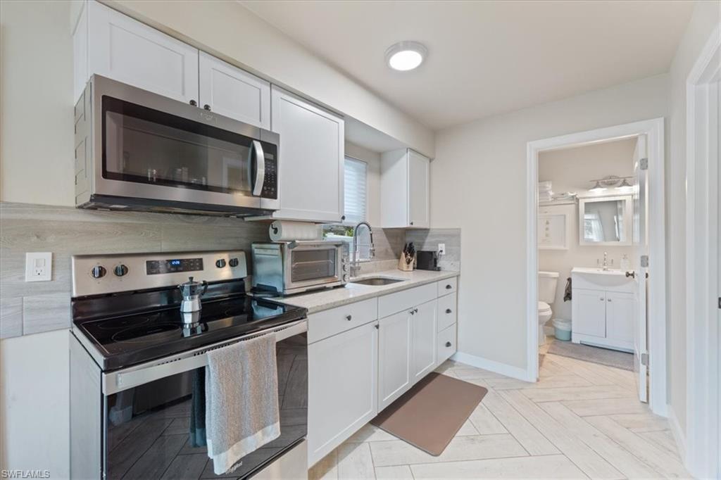 3365-3367 Estey Avenue Naples, FL 34104 - Photo 8 of 30 a kitchen with white cabinets and stainless steel appliances