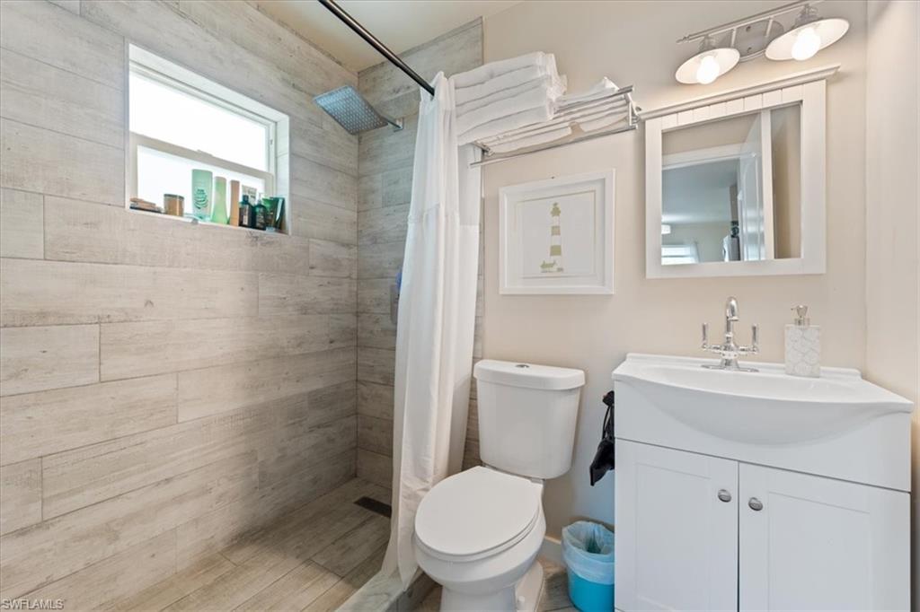 3365-3367 Estey Avenue Naples, FL 34104 - Photo 10 of 30 a bathroom with a toilet a sink a mirror and a shower