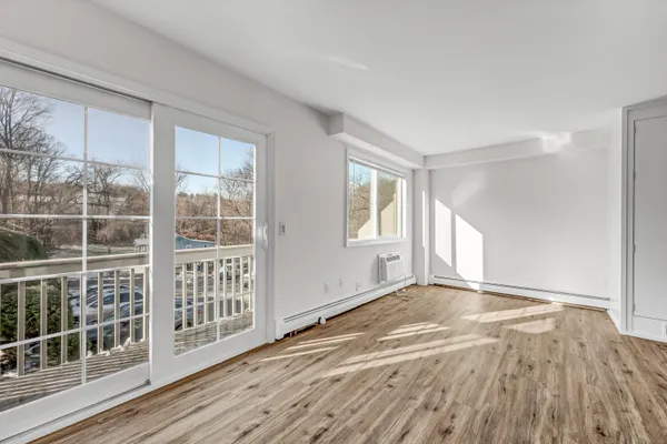 a view of an empty room with wooden floor and a window