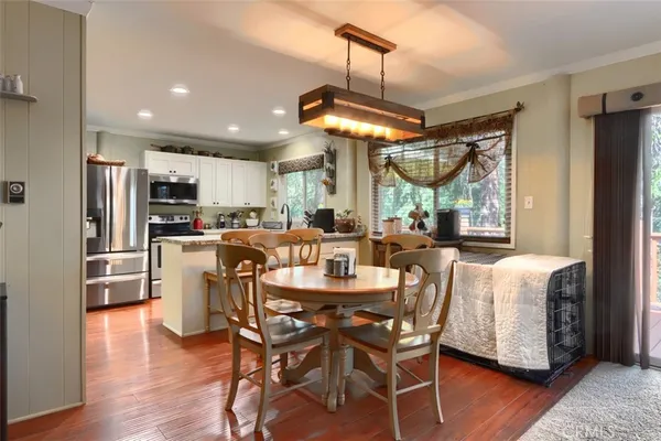 a dining room with stainless steel appliances kitchen island granite countertop a table chairs and a refrigerator