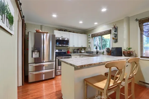 a kitchen with stainless steel appliances granite countertop a refrigerator a stove and a sink with wooden floor