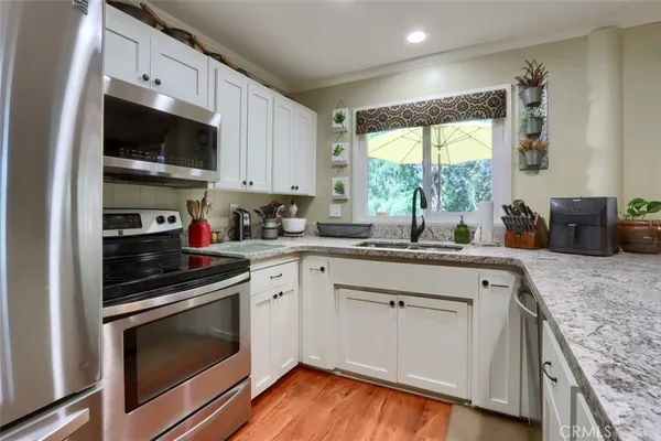 a kitchen with granite countertop a sink cabinets stainless steel appliances and a large window