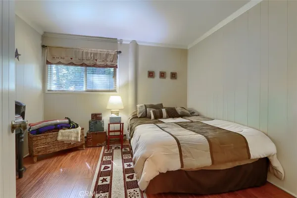 a bed sitting in a bedroom next to a window with wooden floor