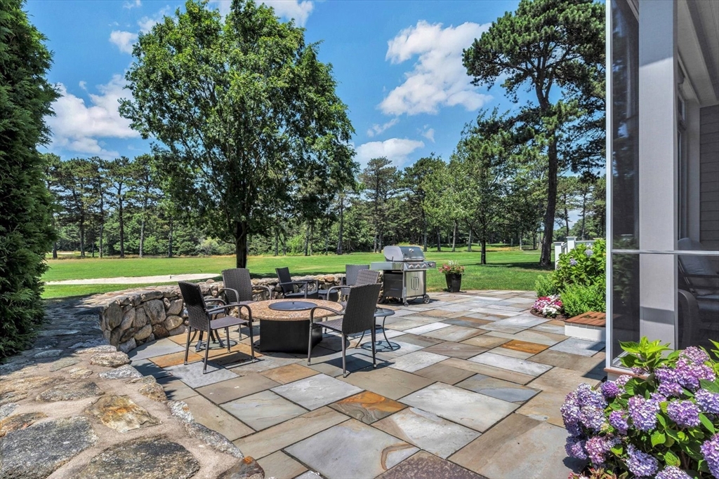 66 A Simons Road, Unit A Mashpee, MA 02649 - Photo 3 of 28 a view of backyard with seating space and trees