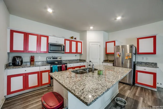 a kitchen with stainless steel appliances granite countertop a stove top oven a sink dishwasher and cabinets with wooden floor