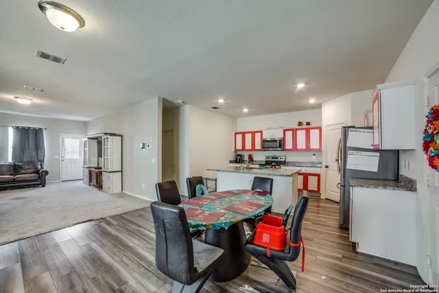 a living room with stainless steel appliances furniture a dining table and kitchen view