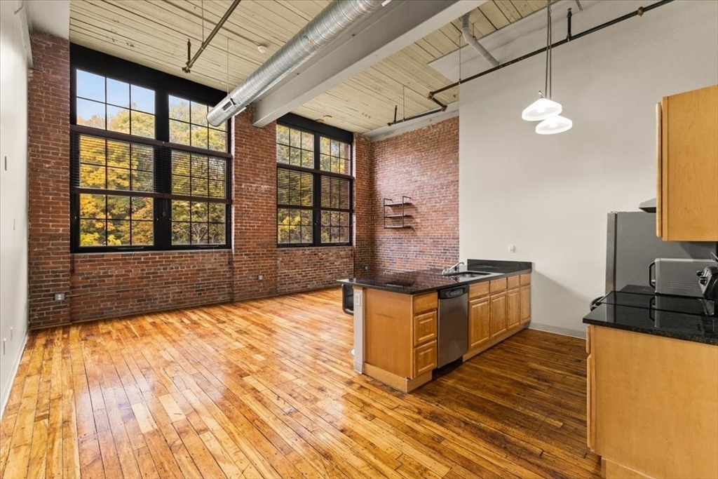 685 Social Street, Unit 215 Woonsocket, RI 02895 - Photo 28 of 40 a kitchen with stainless steel appliances granite countertop a stove a sink and a microwave